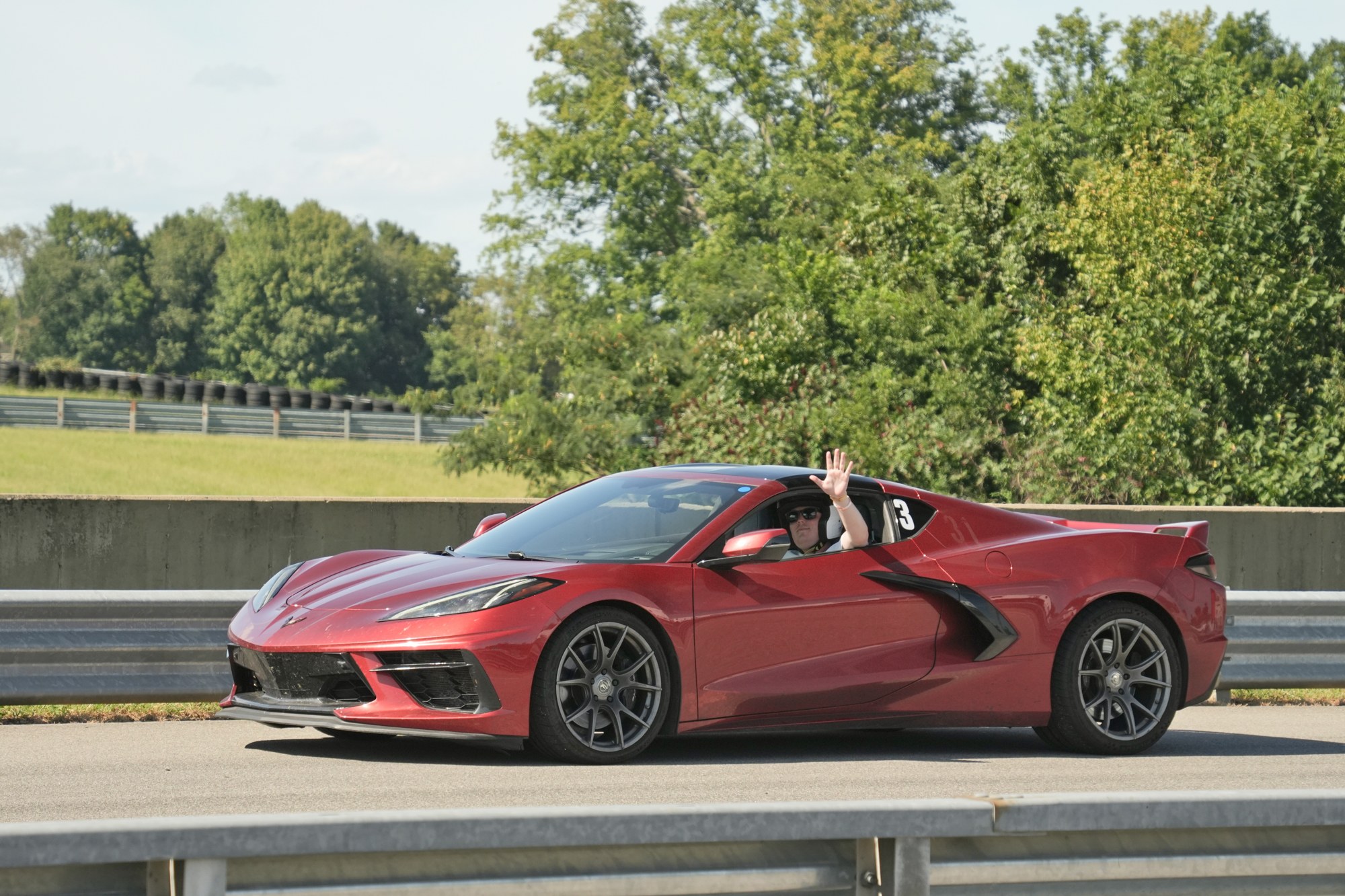 Track-day driver waving from a Corvette